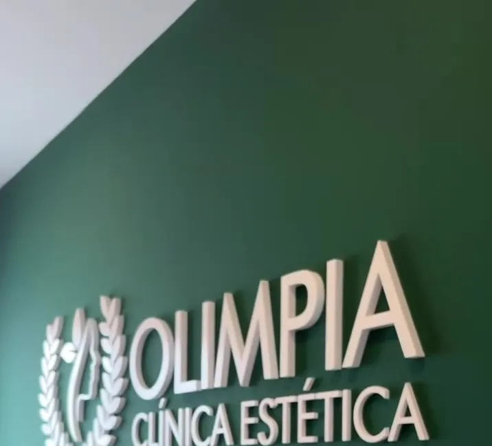 Logo de Olimpia en relieve sobre la pared verde de la clínica